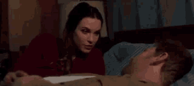 a woman is laying on a man 's chest in a bed .