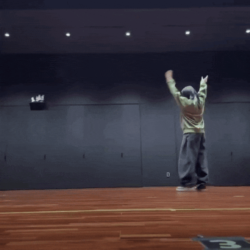 a person doing a handstand on a wooden floor with the letter m on the floor
