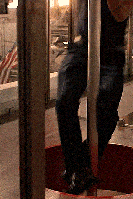 a person standing on a pole in front of a window with an american flag in the background