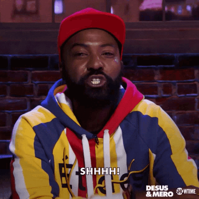 a man with a beard is wearing a colorful sweatshirt that says shhhh on it