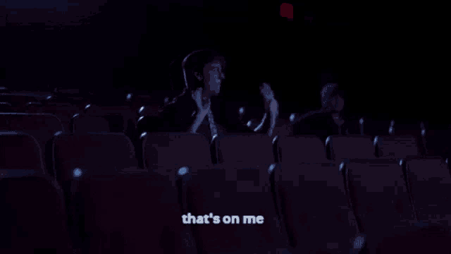 a person sitting in a dark auditorium with the words that 's on me written on the bottom