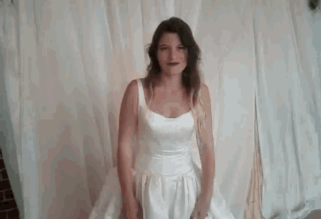a woman in a white wedding dress is standing with her arms in the air .