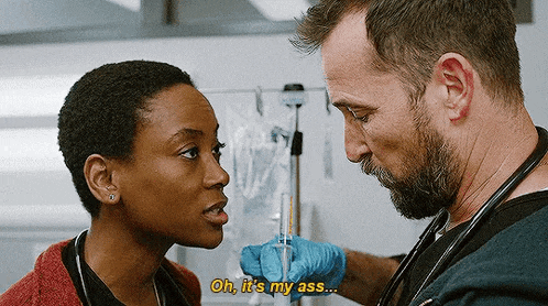 a man with a beard is holding a syringe and talking to a woman in a hospital room .