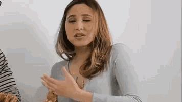 a woman is eating a croissant and making a funny face while talking to a man .