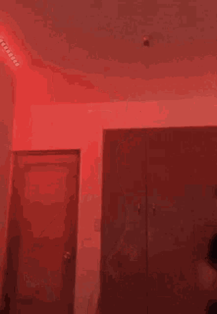 a man is dancing in a room with red lights on the ceiling .