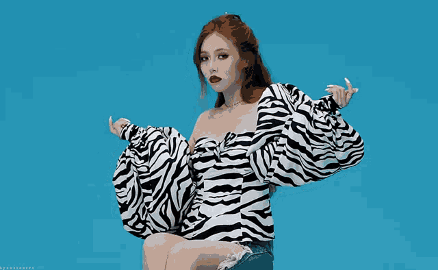 a woman wearing a zebra print top and jeans