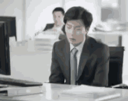a man in a suit is sitting at a desk in front of a computer .