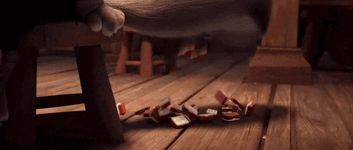 a cat 's paw is laying on a wooden floor next to a pile of broken cards