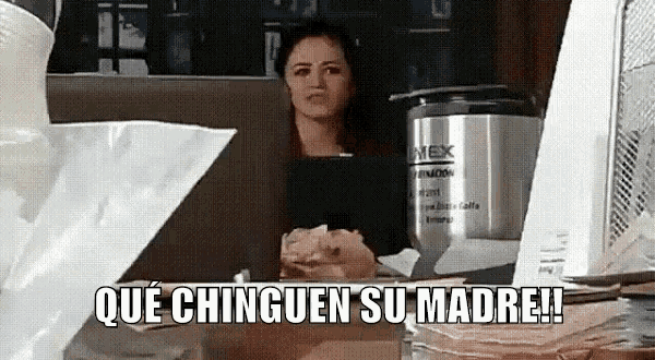 a woman is sitting at a table with the words que chinguen su madre written on the screen .
