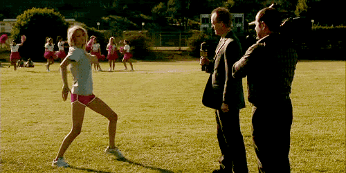 a group of cheerleaders are on a field with a reporter