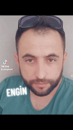 a man with a beard is wearing sunglasses and a green shirt that says engine
