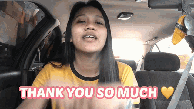 a woman in a yellow shirt is sitting in a car and says thank you so much