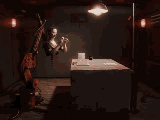 a woman is sitting at a table with a robotic arm attached to her head
