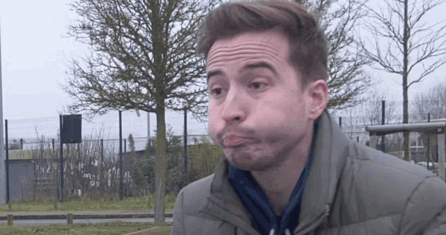 a man making a funny face in front of a fence