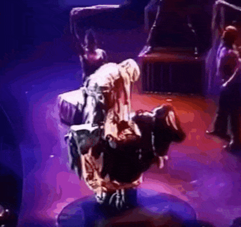 a group of people are performing on a stage with purple lights .