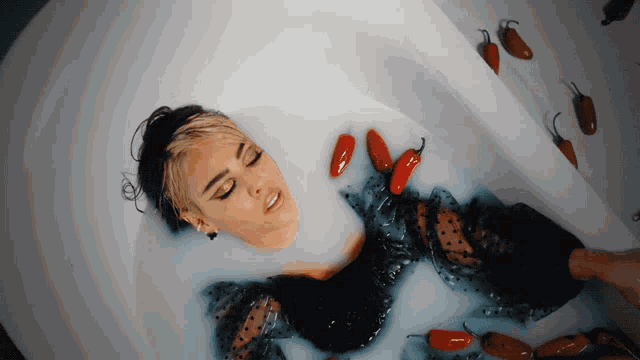 a woman is laying in a bathtub with jalapenos on the floor