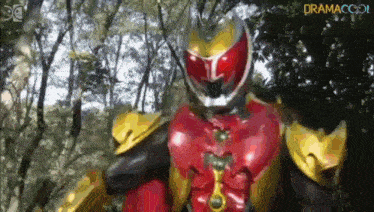 a superhero is standing in the woods wearing a red and gold costume .