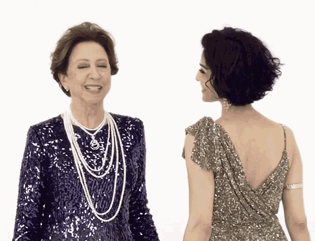 two women are standing next to each other and one is wearing a sequined dress