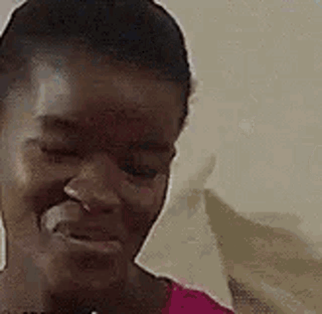 a close up of a woman 's face with her eyes closed and a pink shirt on .