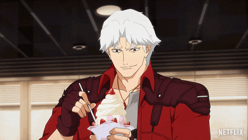 a man in a red jacket is eating an ice cream sundae with strawberries and whipped cream