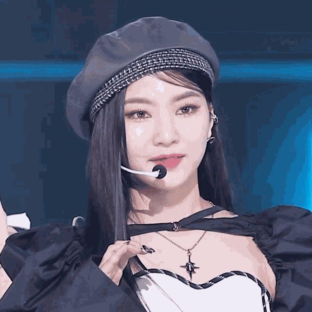 a woman wearing a beret and a necklace holds a microphone in her mouth