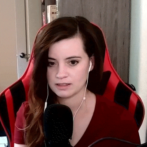 a woman wearing headphones and a red shirt is sitting in a red gaming chair .