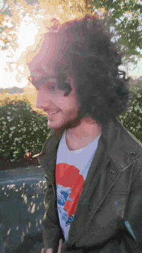 a man with long curly hair and a beard wearing a t-shirt with a picture of a dragon on it