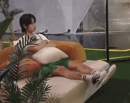 a young man is laying on a couch with a bunch of pillows on it .