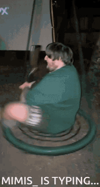 a man in a green shirt is sitting on a green circle with the words mimis_is typing below him