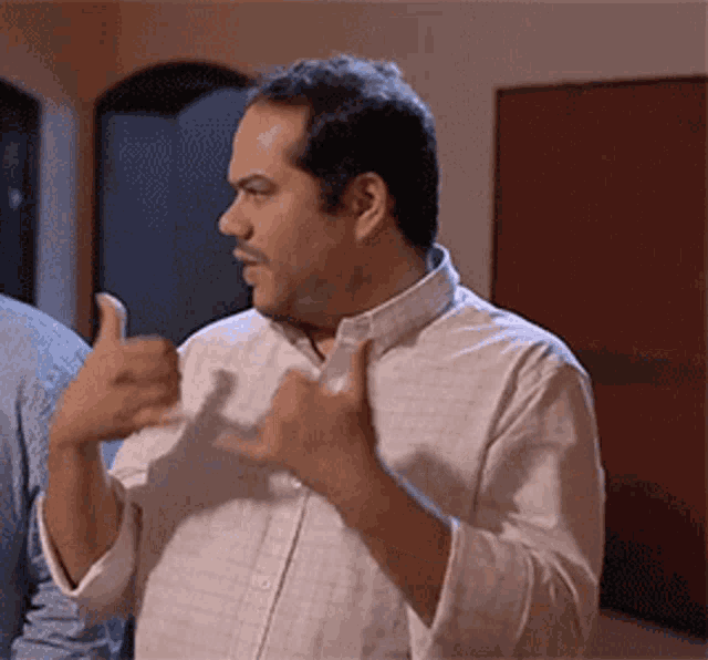 a man in a white shirt gives a thumbs up