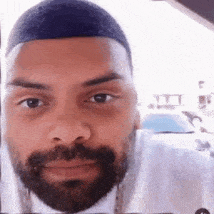 a close up of a man 's face with a beard looking at the camera .