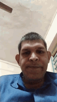 a man in a blue shirt is looking down at the camera