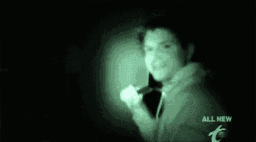 a man in a hoodie is holding a flashlight in the dark .