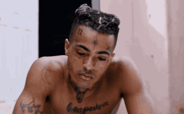 a shirtless man with a tattoo on his forehead that says ix