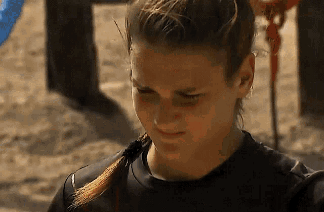 a woman with a ponytail and a black shirt is standing in the sand