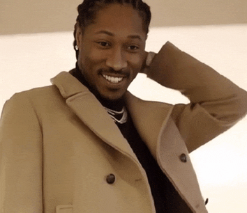 a man wearing a tan coat is smiling with his hand on his head