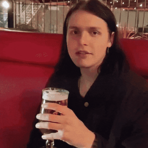 a woman is holding a glass of beer in her hand