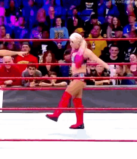 a woman in red boots is standing in a wrestling ring with a crowd watching .