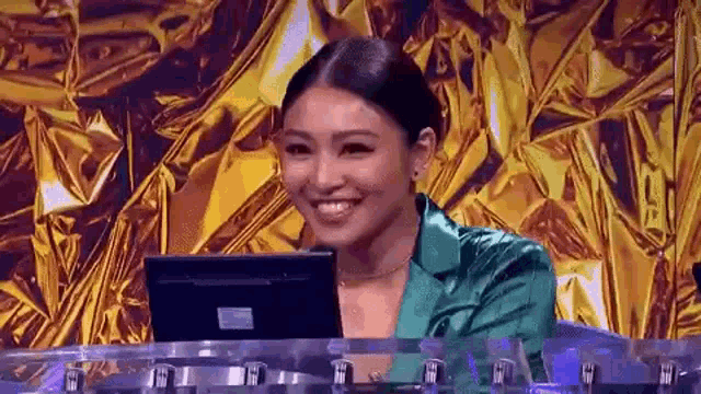 a woman in a green jacket is sitting at a table with a laptop computer .
