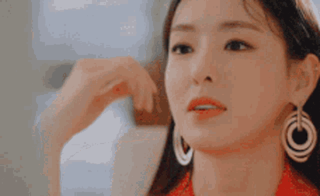 a close up of a woman wearing a red dress and earrings .
