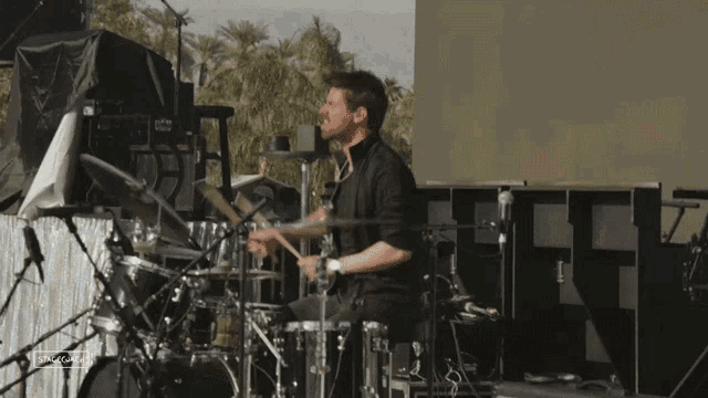 a man playing drums in front of a screen that says ' s-nova '