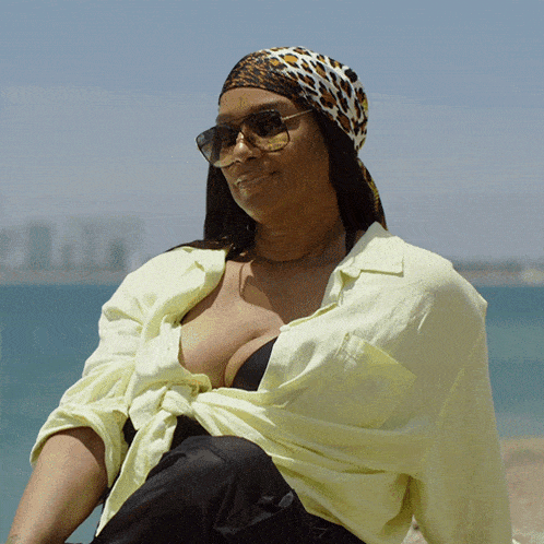 a woman wearing sunglasses and a leopard print scarf sits on the beach