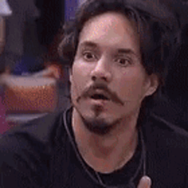 a man with a beard and mustache is wearing a black shirt and ear buds .