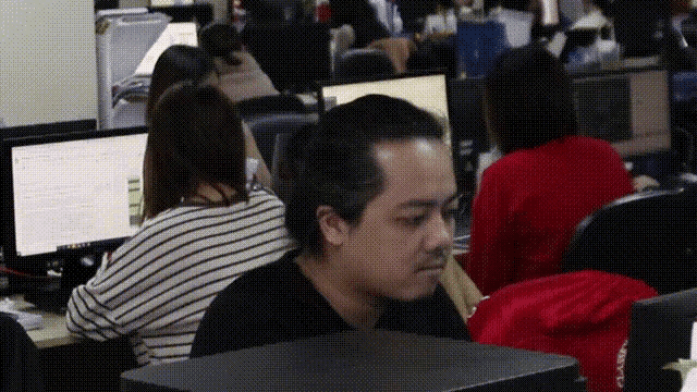 a man in a black shirt sits in front of a computer monitor