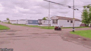 a man is riding a red lawn mower down a dirt road .