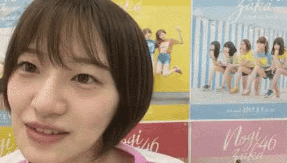 a close up of a woman 's face in front of a wall with posters on it .