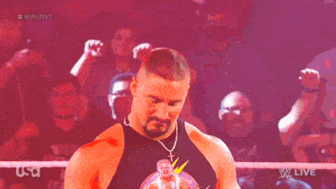 a man in a wrestling ring is holding a microphone in front of a crowd that is cheering