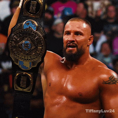 a shirtless wrestler holds up a heavyweight championship belt