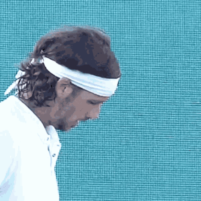 a man wearing a white headband looks down