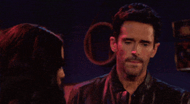 a man and a woman are looking at each other in a bar